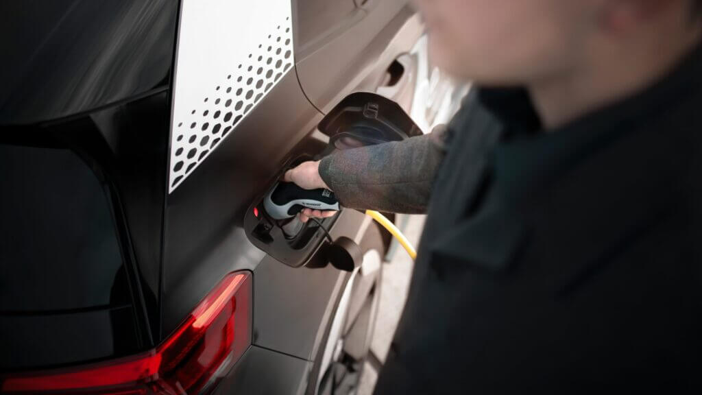 Un homme recharge une voiture électrique